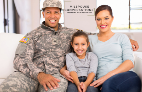 A family sitting on a couch with a soldier and a child.