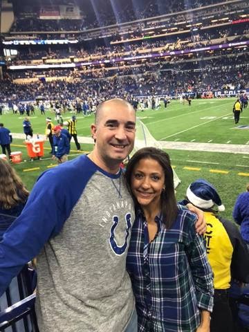 A man and woman posing for a photo at a football game.