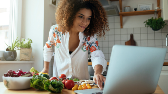 A woman using a laptop on a kitchen counter.