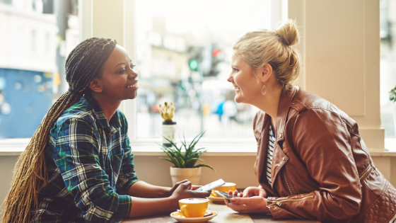 Two women talking at a table in a cafe.