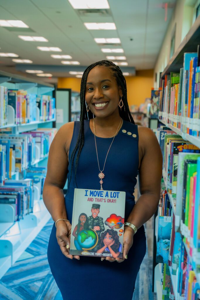 A woman holding up a book in front of bookshelves.