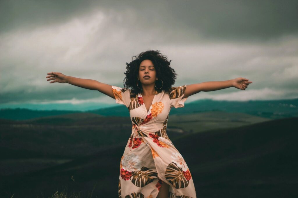 A woman in a dress standing on top of a hill.