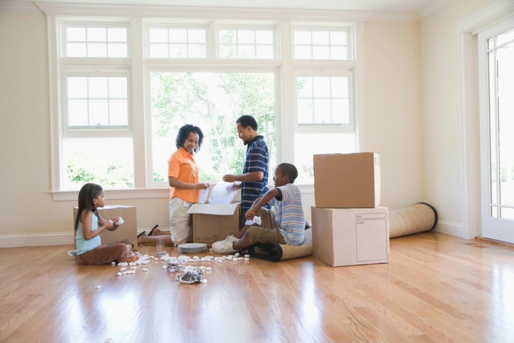 A group of people in the living room with boxes.