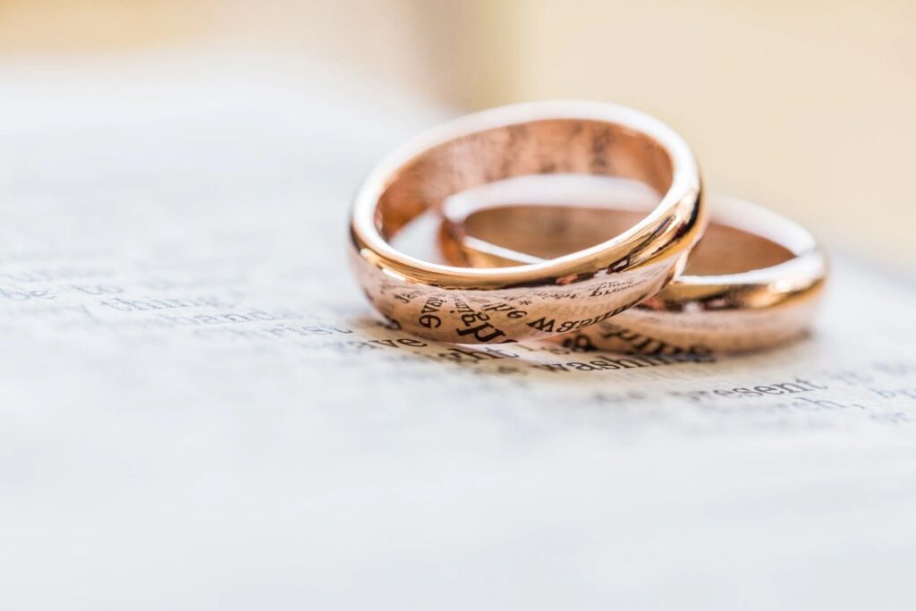 Two gold wedding rings on top of a wooden table.