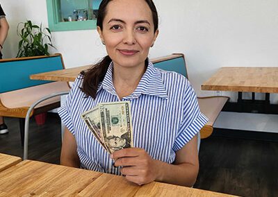 A woman sitting at a table with money in her hands.