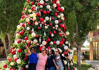 A group of women posing in front of a christmas tree.